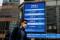 A man walks past a screen displaying the Hang Seng Index at Central district, in Hong Kong