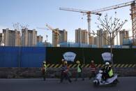 Workers walk past a construction site near residential buildings in Beijing