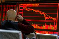 An investor sits in front of a board showing stock information at a brokerage office in Beijing