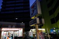 The signboards of a 7-Eleven store are partially switched off as Japanese government issues warning over possible power crunch due to heatwave in Tokyo
