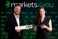 Ms. Marina Strausa holding an autographed cricket bat alongside Mr. AB de Villiers. FX Empire