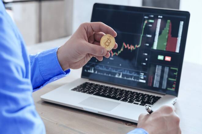 Trader with bitcoin in his hands using Octa platform in a laptop. FX Empire