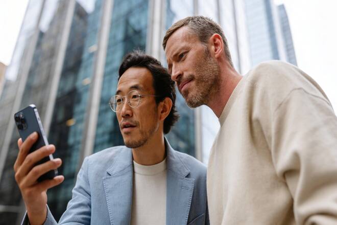 Traders using Elev8 platform on their smartphone, in front of a skyscraper