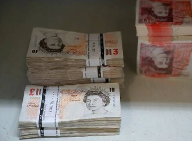 Wads of British Pound Sterling banknotes are stacked
