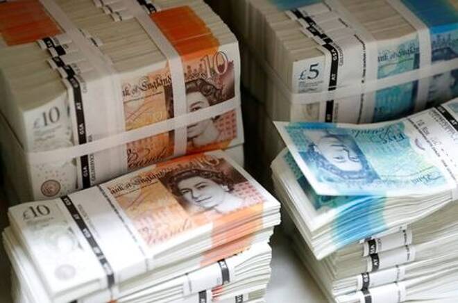 Wads of British Pound Sterling banknotes are stacked