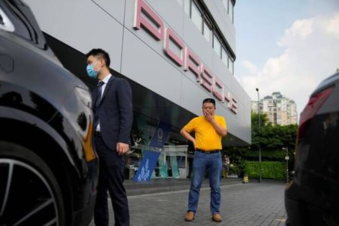 Guo Hui looks at his Porsche Cayenne he is selling to pay his debts, at a car dealership in Guangzhou