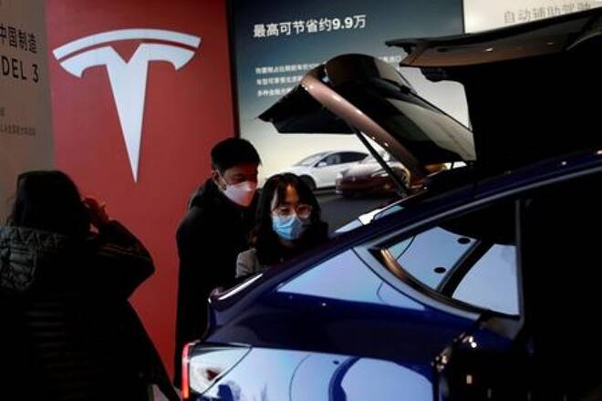 Visitors wearing face masks check a China-made Tesla