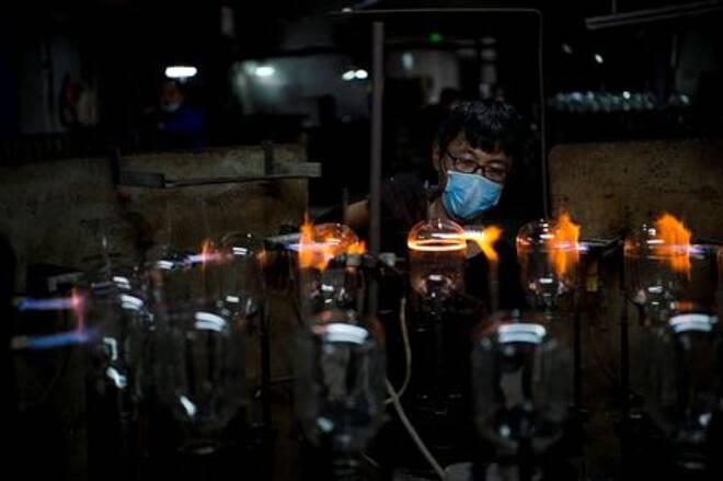 Worker wearing a face mask works on a production line manufacturing glassware products at a factory in Haian, Jiangsu