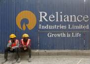 FILE PHOTO: Labourers rest in front of an advertisement of Reliance Industries Limited at a construction site in Mumbai