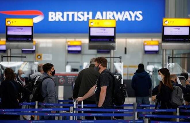 Passengers stand in a queue to the British Airways check-in