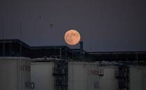 FILE PHOTO: The moon rises behind oil storage tanks in Omsk