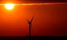 The sun rises behind an electric power windmill