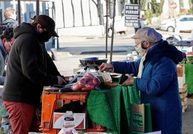 A lady pays for fruit and vegetables from a market