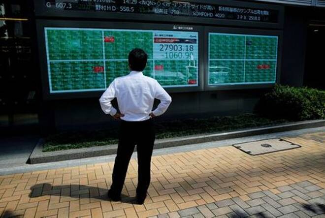 FILE PHOTO: A man watches an electric board showing Nikkei index outside a brokerage at a business district in Tokyo