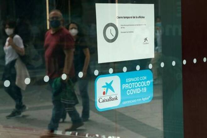 People walk past a closed Caixabank's branch during a one-day