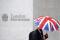Pessoa se protege da chuva ao passar em frente ao prédio da Bolsa de Londres