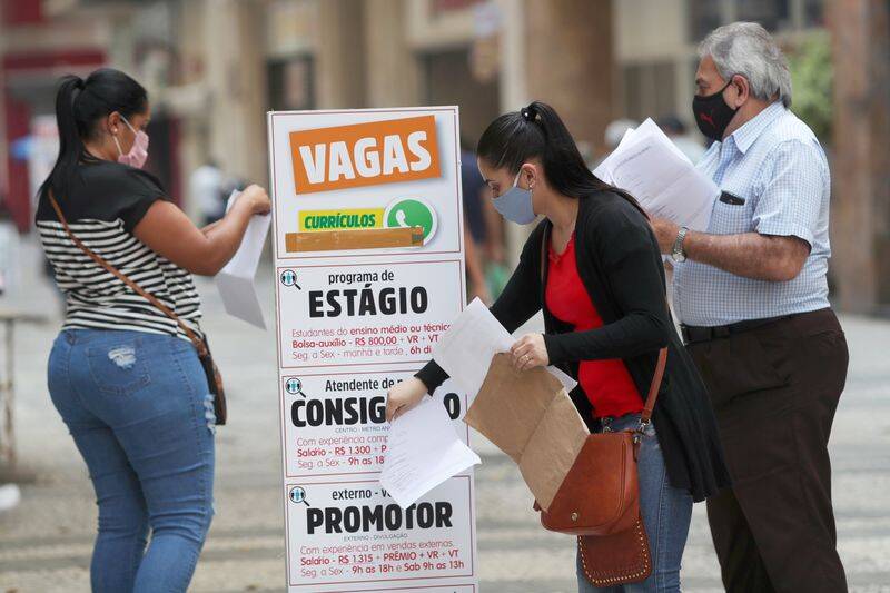 Mulher coloca currículo em caixa ao lado de anúncios de empregos, em São Paulo, Brasil