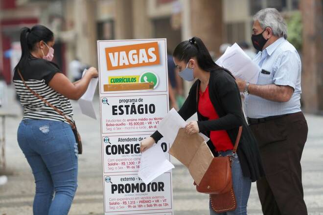 Mulher coloca currículo em caixa ao lado de anúncios de empregos, em São Paulo, Brasil