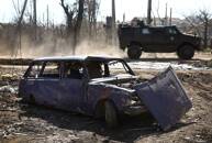 Veículo militar passa por carro destruído durante combates em Bakhmut, Ucrânia