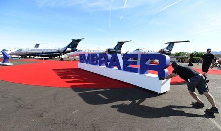 Funcionários ajeitam letreiro da Embraer durante exposição em Las Vegas.