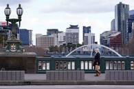 Mulher atravessa ponte no centro da cidade enquanto o Estado