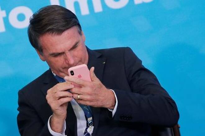 Presidente Jair Bolsonaro mexe em telefone celular durante cerimônia no
