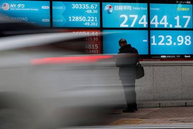 FOTO DE ARCHIVO: Un hombre frente a una pantalla que muestra el índice de acciones Nikkei y los índices bursátiles mundiales en el exterior de una agencia de valores, en Tokio