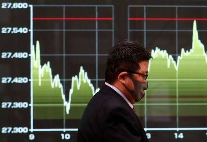 Imagen de archivo de un hombre con mascarilla caminando frente a una pantalla que muestra un gráfico de los movimientos recientes del índice Nikkei afuera de una correduría en Tokio