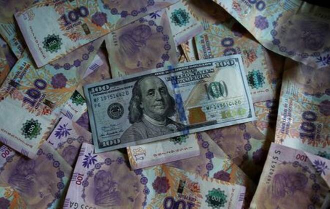 Un billete de cien dólares estadounidenses reposa sobre billetes devaluados de cien pesos de Argentina en esta ilustración fotográfica