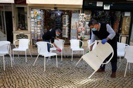 Trabajadores limpiando sillas para abrir la terraza de un restaurante