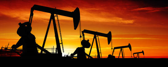 oil pumpjacks in silhouette at sunset, panoramic frame