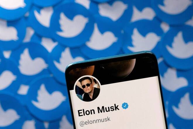 Foto de archivo del perfil de Twitter de Elon Musk en un smartphone junto a logos impresos de la compañía