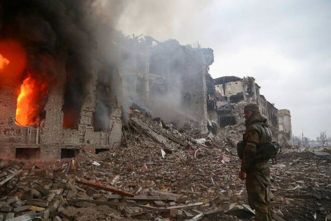 A service member of pro-Russian troops stands in front of a destroyed building in Mariupol