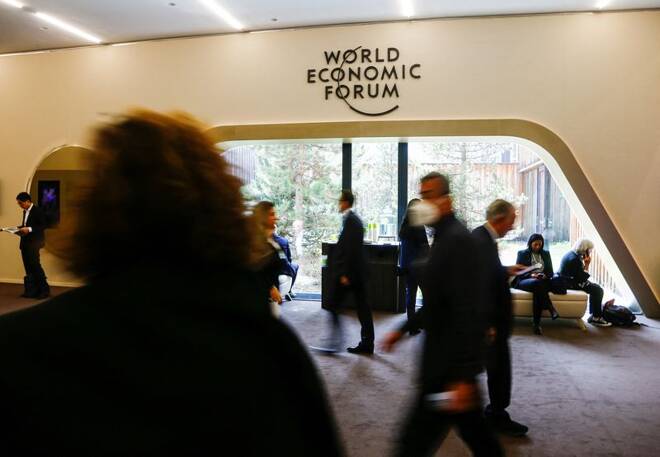 Personas caminando frente al logo del Foro Económico Mundial durante las reuniones en Davos, Suiza