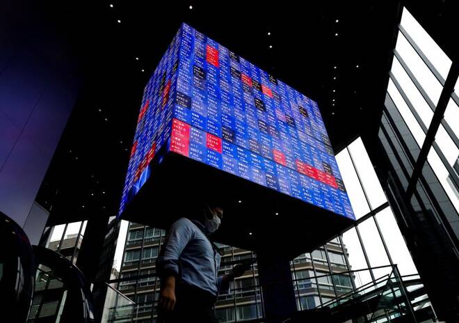 FOTO DE ARCHIVO: Un hombre camina bajo una pantalla electrónica que muestra el índice de precios de las acciones Nikkei de Japón dentro de una sala de conferencias en Tokio