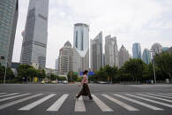 Imagen de archivo de una persona cruzando una calle frente al distrito financiero de Lujiazui, en Shanghái, China.