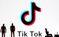 Ilustración fotográfica con figuras impresas en 3D situadas frente al logo de la aplicación de videos cortos china Tik Tok.