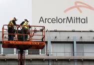FOTO DE ARCHIVO: Trabajadores de pie cerca del logotipo de ArcelorMittal