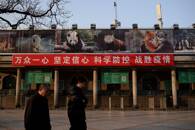 Unas personas pasan junto a una pancarta colgada en la taquilla del zoo de Pekín, cerrado tras un brote del COVID