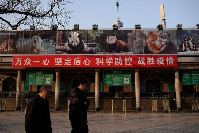 Unas personas pasan junto a una pancarta colgada en la taquilla del zoo de Pekín, cerrado tras un brote del COVID