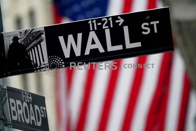 Il cartello stradale di Wall Street davanti a una bandiera statunitense a New York