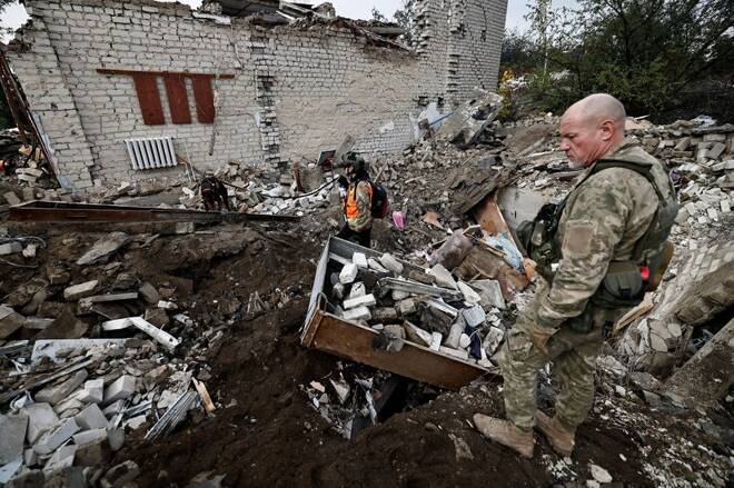 Vigili del fuoco e soldati dell'esercito ucraino cercano i corpi delle persone uccise durante un attacco russo, tra i resti di un edificio accanto a una torre televisiva, nella città di Izium, recentemente liberata.