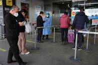 Dei viaggiatori entrano in una sala del terminal dell'Aeroporto Internazionale di Pechino (Beijing Capital International Airport)