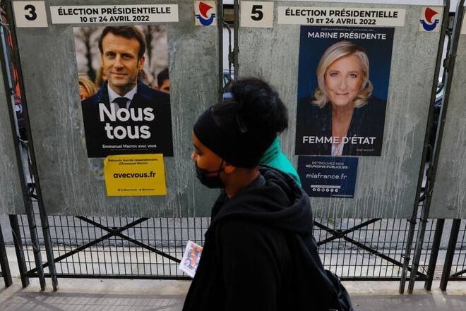 Due persone davanti a due manifesti per le elezioni presidenziali francesi, rispettivamente del presidente Emmanuel Macron e la candidata Marine le Pen, a Parigi