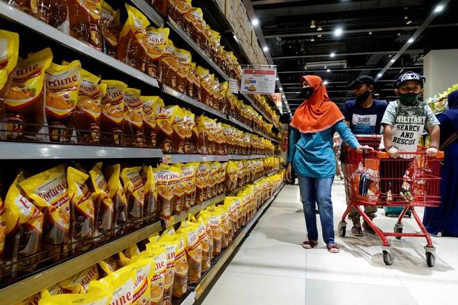 Una famiglia in un supermercato davanti a confezioni di olio di palma a Giacarta, in Indonesia