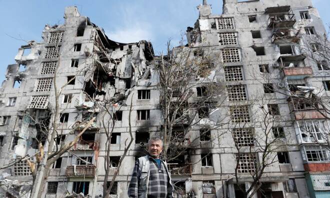 Un uomo davanti a diversi palazzi distrutti dai bombardamenti a Mariupol