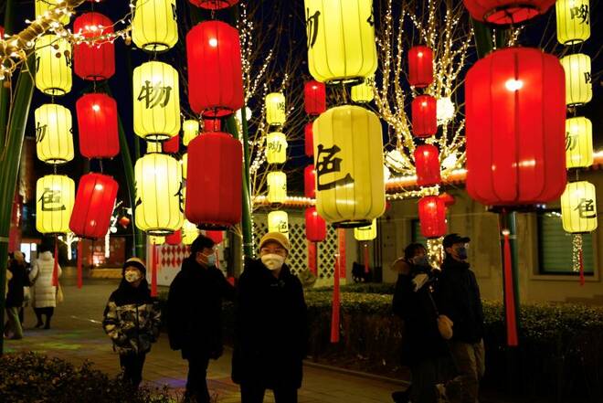 Diversi passanti per una strada illuminata da lanterne per il Capodanno lunare a Pechino