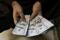 Un uomo conta banconote da 100 dollari statunitensi a Peshawar, in Pakistan