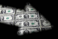 Una serie di banconote da 1 e 2 dollari visti attraverso la silhouette di un grafico