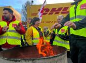 ARCHIV: Arbeiter stehen neben einer Feuertonne während eines bundesweiten Warnstreiks bei der Deutschen Post in Köln, Deutschland